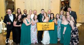 Kaitlyn Rooney Buresh and Saint Rose alumni friends at her wedding holding a Saint Rose banner
